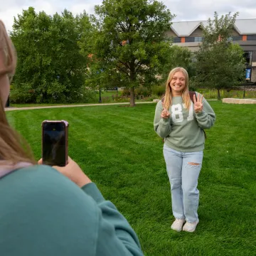 A student poses on campus for her friend who is taking the photo. 