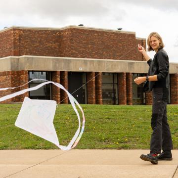 student flying white kite on Barron County campus 