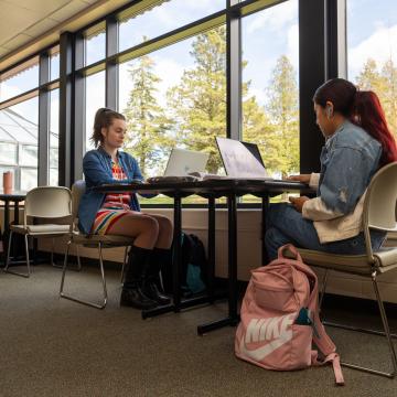 two students study at a window table at UWEC-BC 