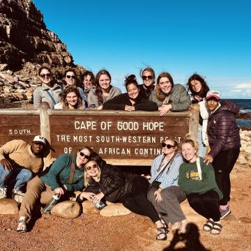 Students pose in front of a sign that reads "Cape of Good Hope"