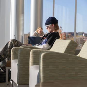 A student studies in the sunlight near a window.