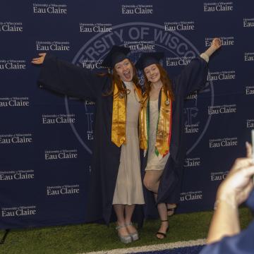 Students smile with their hands in the air celebrating graduation day.