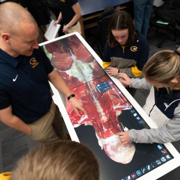Students work on the anatomage table alongside a faculty member.