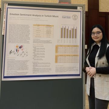 Honors student Nguyen Nguyen stands in front of a poster presentation