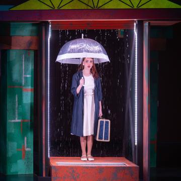 Woman with clear umbrella in an elevator holding a suitcase 