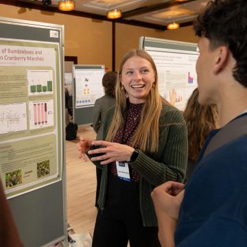 A student brightly smiles as she shares her research findings during CERCA.