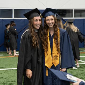 Two students smile together for a photo following Commencement.