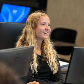 A student smiles as she works on a computer during Orientation.