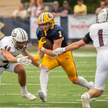 Blugold Football player runs with the football during the Football Opener.