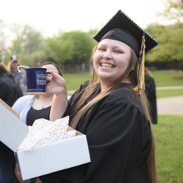female graduate holding a UW-Eau Claire Barron County coffee mug