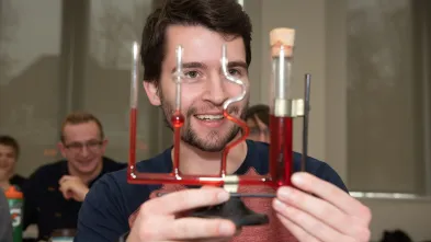 Physics student holding a water filled pressure instrument 