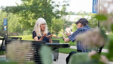 two people using sign language at a table outside