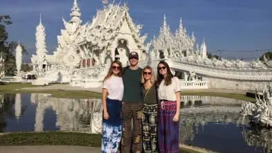 A group photo of students on a study aboard trip to Thailand posting in front of the white temple