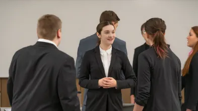 Woman wearing a black suit speaks with another woman