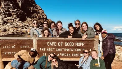 Students pose in front of a sign that reads "Cape of Good Hope"