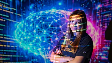 Artificial intelligence major poses in front of digital screen