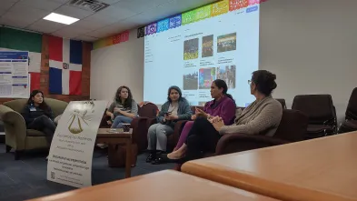 A panel of speakers sit in front of a projector screen at an event.