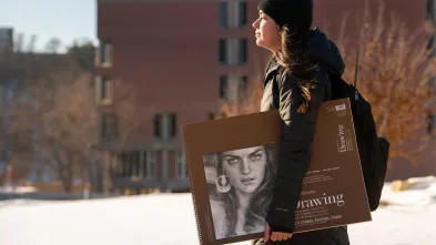 Student walking to class with drawing book
