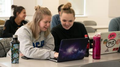 two students in classroom on laptops