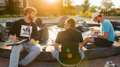 A group of student sit around a fountain at lower campus.  