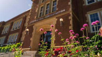 Pink flowers in front of Schofield Hall on a sunny day.