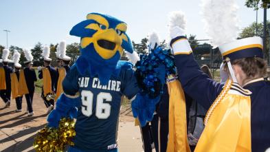 Blu the mascot high-fives a member of Blugold Marching Band