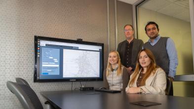 research team group shot in computer lab, two seated, two standing 