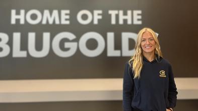 UWEC student Sydney Hoffman stands in front of the UWEC Home of the Blugolds sign