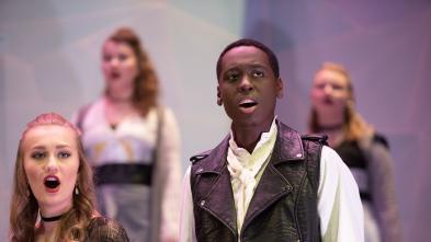 A group of students sing on stage during a performance
