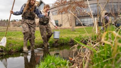 Honors students Hannah Schindler and Lexi Siegmund in camouflage waders