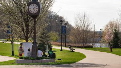 An outdoor class takes place under the clock tower on campus