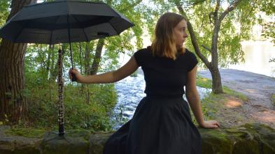 Carrie Schwartz in a black dress in the forest holds an umbrella over an oboe 
