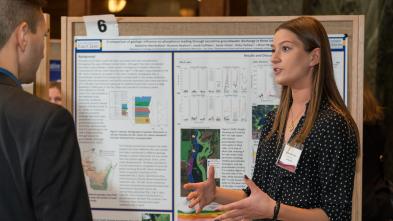 female student describing her research to listener in the Research in the Rotunda event