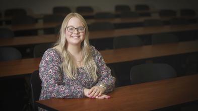 Grace Olson, female NCUR research student sitting at a desk, long blond hair, smiling.