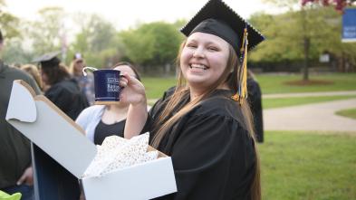 female graduate holding a UW-Eau Claire Barron County coffee mug