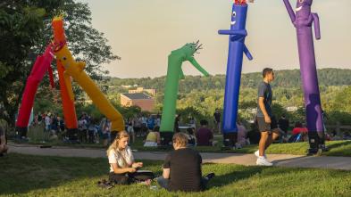 Rainbow inflatable people and students walking past