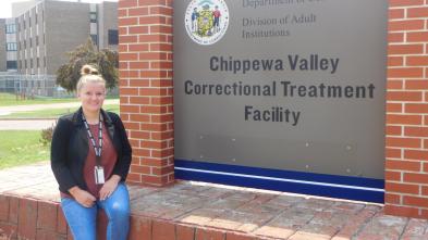 female student seated in front of signage at the Chippewa Valley Correctional Treatment Facility