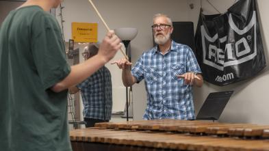Jeffrey Crowell, music profesor, in a small group percussion lesson in Haas Fine Arts with two students, one make and one female.