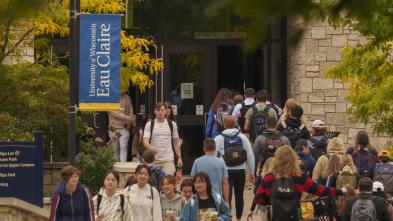 Student crowd walking into and out of Davies Center, lighted screen over entry says Chase Your Dreams.