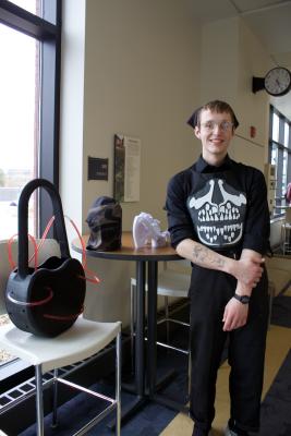 Student smiling next to art project.