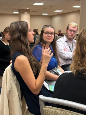 student presenting at a conference, talking while other students watch
