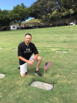 John Kinville kneeling at a veteran gravesite 