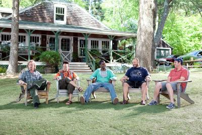 Five men sitting outside a Cabin talking.