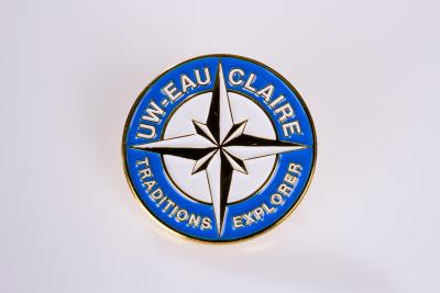 UW-Eau Claire Traditions Keeper lapel pin. The pin is blue and white with a compass arrow in the middle.