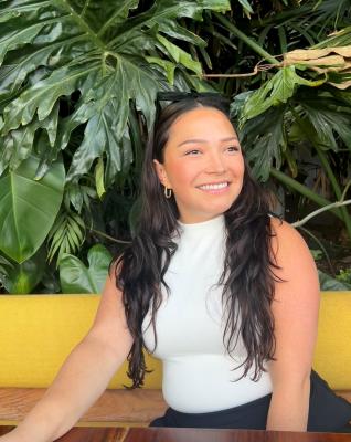 Helue Leslie-Vazquez, on a bench wiht tropical plants behind her