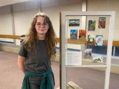 Abby Hable poses next to postcards included in the "The Small and the Mighty: Chippewa Valley" exhibit