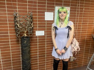 Deanna Schmalz poses next to her sculptural piece titled "Never Again is Now"