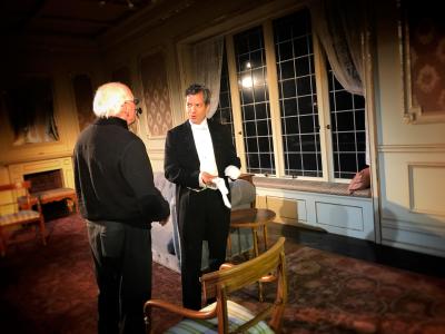 Two men on stage, one in black tuxedo