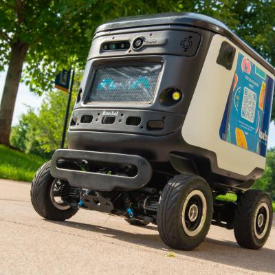 A Kiwibot travels on a campus sidewalk.