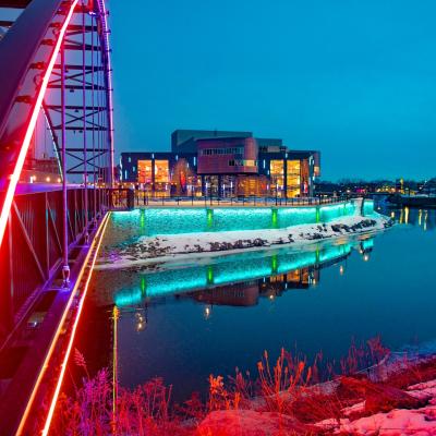 Pablo Center at sunset with colorful lights lighting up the bridge and river